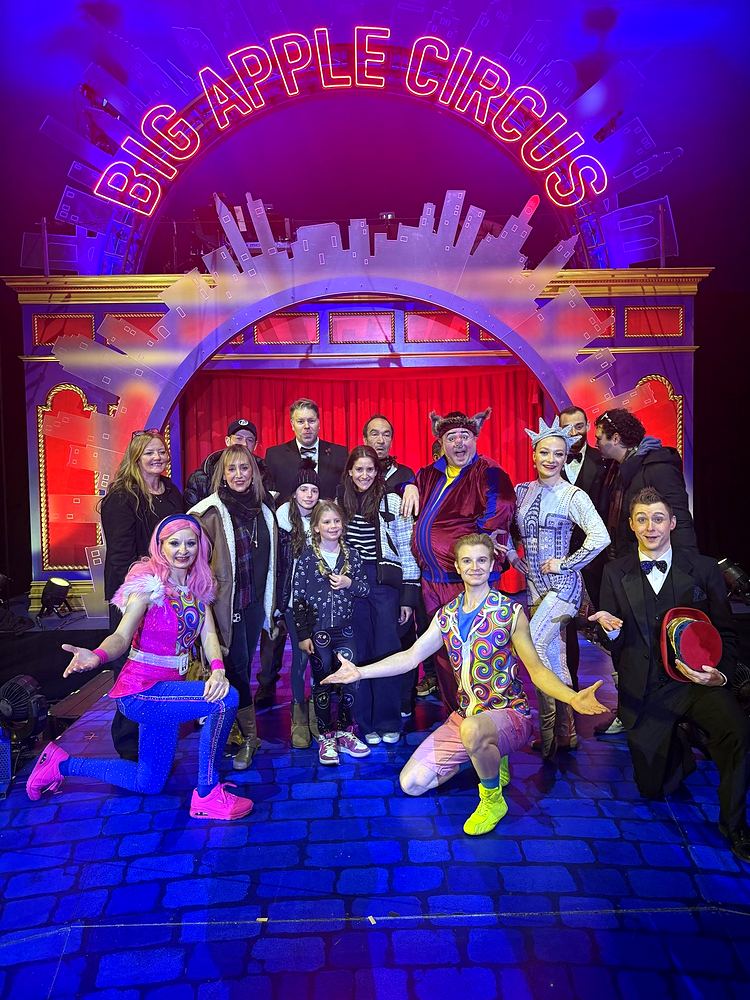 Big Apple Circus Hometown Playground: the company in costume, including a pink-haired clown and a Statue of Liberty character, under the Big Apple Circus sign. Costume design by Cynthia Nordstrom