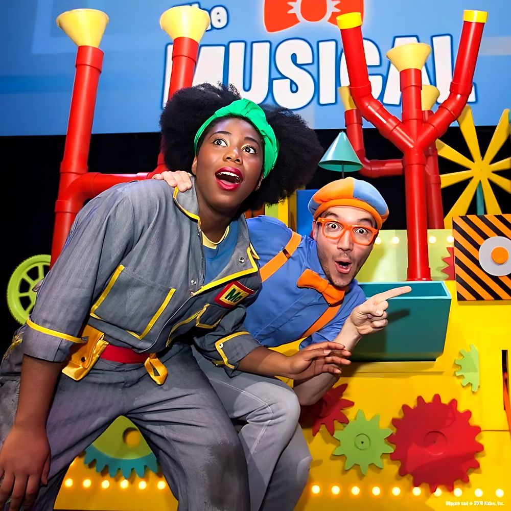 Meekah in gray coveralls and a green headband with Blippi on a pipe set, Blippi The Musical. Costume design by Cynthia Nordstrom