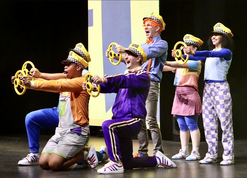 Kids ensemble in patterned caps and color-block outfits holding gears, Blippi The Musical. Costume design by Cynthia Nordstrom