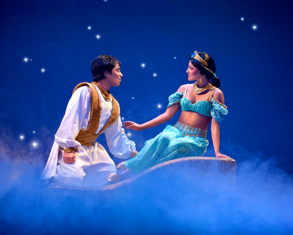 Aladdin in a white vest and Jasmine in teal on a magic carpet under stars, Mickey's Music Festival. Costume design by Cynthia Nordstrom