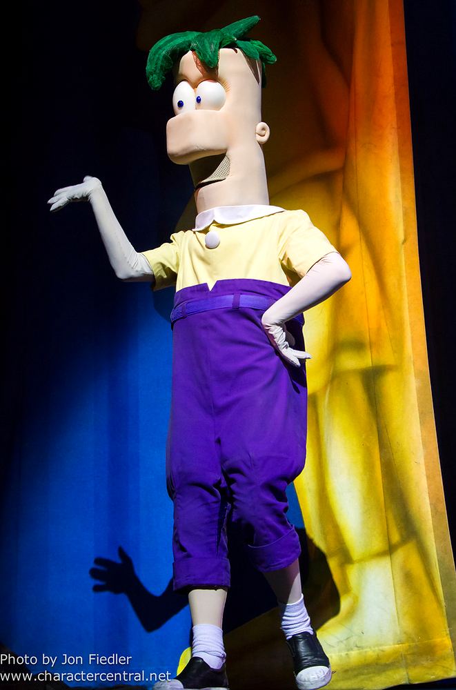 Ferb character in a yellow shirt and purple overalls on stage, Phineas and Ferb Live. Costume design by Cynthia Nordstrom