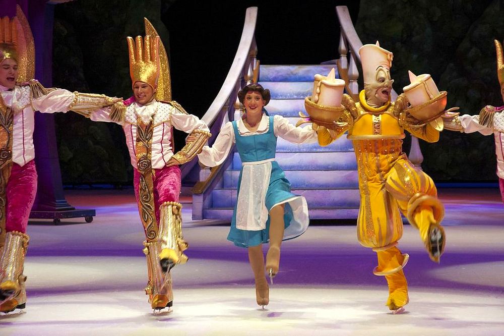 Belle in a blue dress skating between Lumiere and Cogsworth with dancers, Rockin' Ever After. Costume design by Cynthia Nordstrom