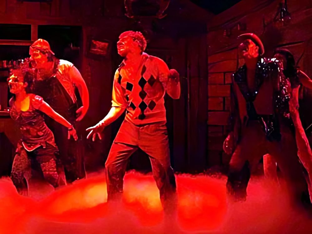 Deadite cast in sweaters and plaid under red light and fog, Evil Dead: The Musical. Costume design by Cynthia Nordstrom