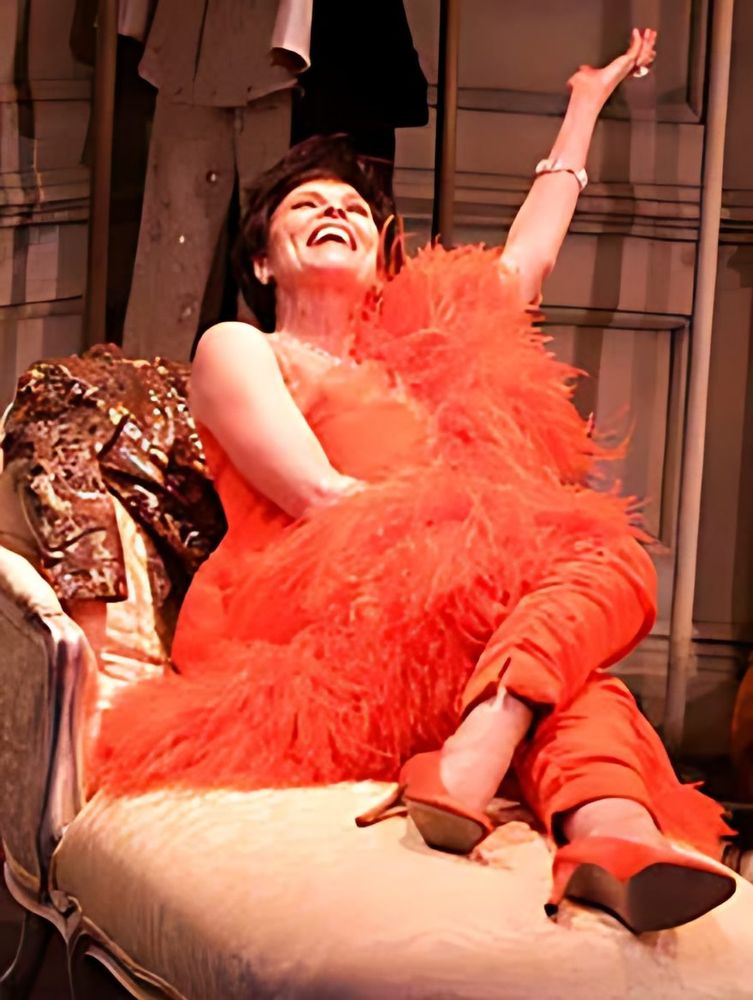 Judy Garland in a red-orange feathered pantsuit lounging on a chaise, This Property Known As Garland. Costume design by Cynthia Nordstrom