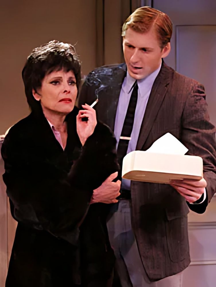 Judy Garland in a black fur coat with cigarette beside a man in tweed, This Property Known As Garland. Costume design by Cynthia Nordstrom