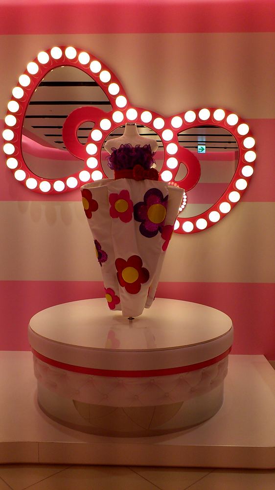White dress with colorful flowers before a lit bow-shaped mirror, Hello Kitty's Wonderland, USJ. Costume design by Cynthia Nordstrom