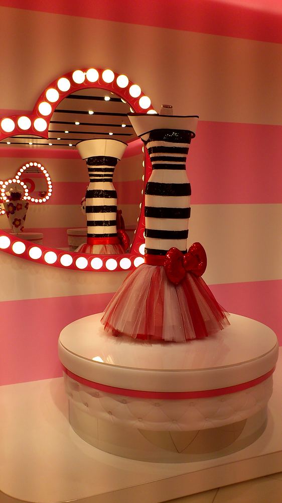 Black and white striped dress with red bow before a bow-shaped mirror, Hello Kitty's Wonderland, USJ. Costume design by Cynthia Nordstrom