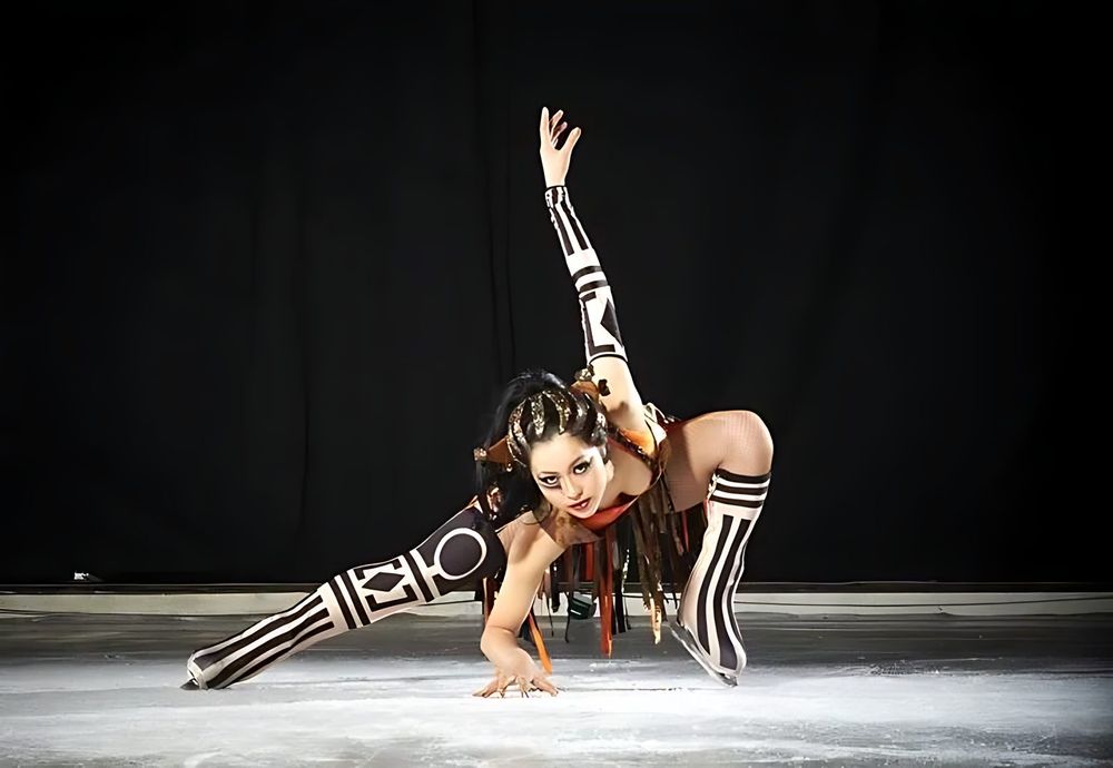 Skater in a black and white graphic striped bodysuit in a low lunge, Holiday On Ice: Speed. Costume design by Cynthia Nordstrom