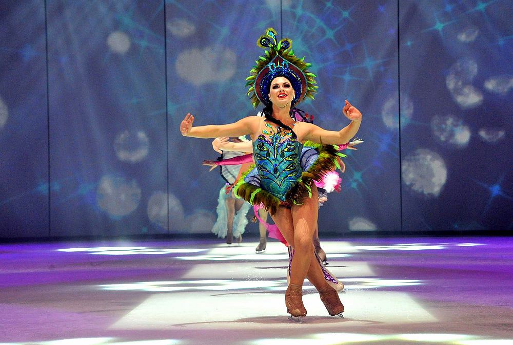 Skater in a teal and pink feathered showgirl costume with headdress, Holiday On Ice: Passion. Costume design by Cynthia Nordstrom
