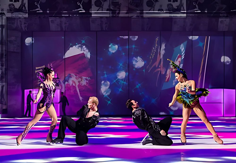 Two women skaters in jeweled costumes with two men kneeling on the ice, Holiday On Ice: Passion. Costume design by Cynthia Nordstrom