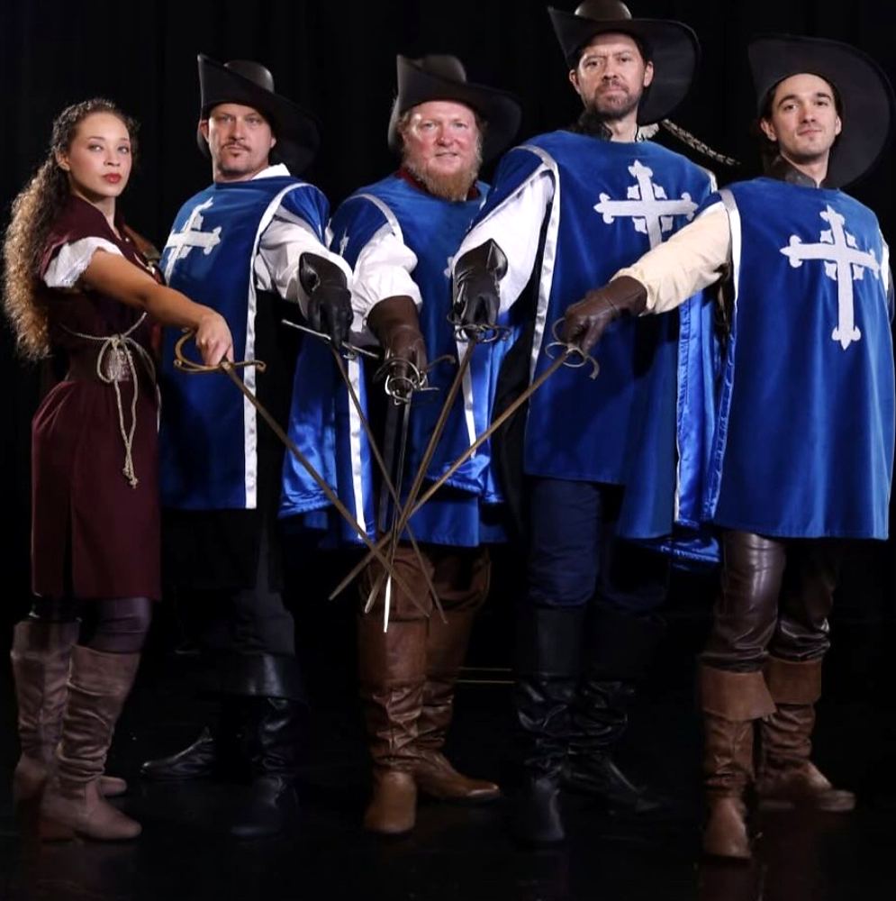 Musketeers in blue tabards crossing swords with a girl in brown, The Three Musketeers. Costume design by Cynthia Nordstrom