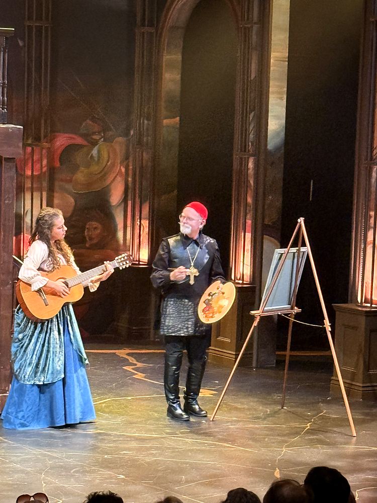Woman in blue with a lute beside a man in black with a painter palette, The Three Musketeers. Costume design by Cynthia Nordstrom