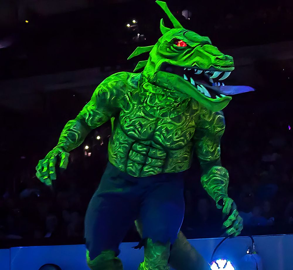 Lizard in a textured green scaly suit with a red-eyed reptile head, Marvel Universe Live. Costume design by Cynthia Nordstrom