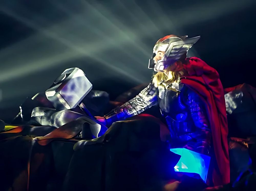 Thor in armor and red cape reaching for his hammer on a rock, Marvel Universe Live. Costume design by Cynthia Nordstrom