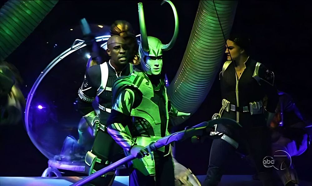 Loki in green with a staff among henchmen in black and green, Marvel Universe Live. Costume design by Cynthia Nordstrom