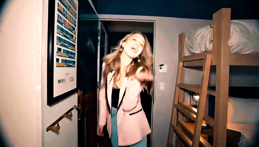 Woman in a pale pink blazer and jeans dancing in a hotel room, Motto by Hilton commercial. Wardrobe design by Cynthia Nordstrom