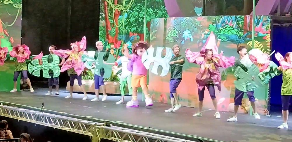 Nickelodeon Live: Está en Ti: dancers in pink and fuchsia flower costumes and dancers with green leaf fans surround Dora in a jungle number. Costume design by Cynthia Nordstrom