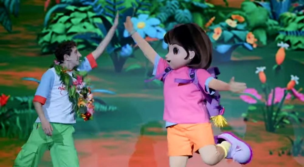 Nickelodeon Live: Está en Ti: the host in a flower lei and jungle print shirt high-fives Dora. Costume design by Cynthia Nordstrom