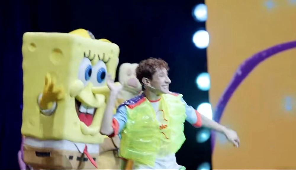 Nickelodeon Live: Está en Ti: the host in an inflatable chartreuse vest dances with SpongeBob. Costume design by Cynthia Nordstrom