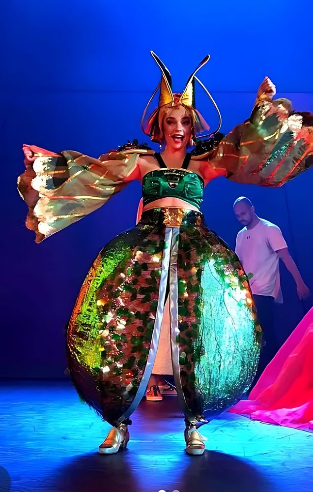 ONE de Musical: a performer in a green sequined gown with a gold headdress. Costume design by Cynthia Nordstrom