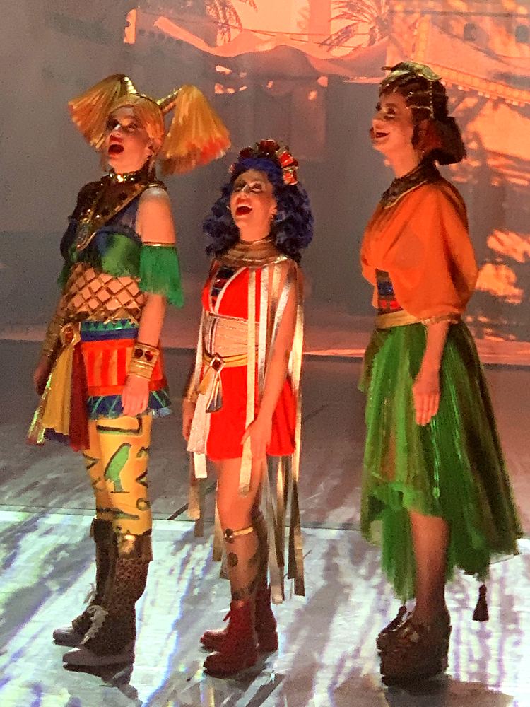 Three women in colorful patchwork costumes and headpieces, close up, ONE de Musical. Costume design by Cynthia Nordstrom