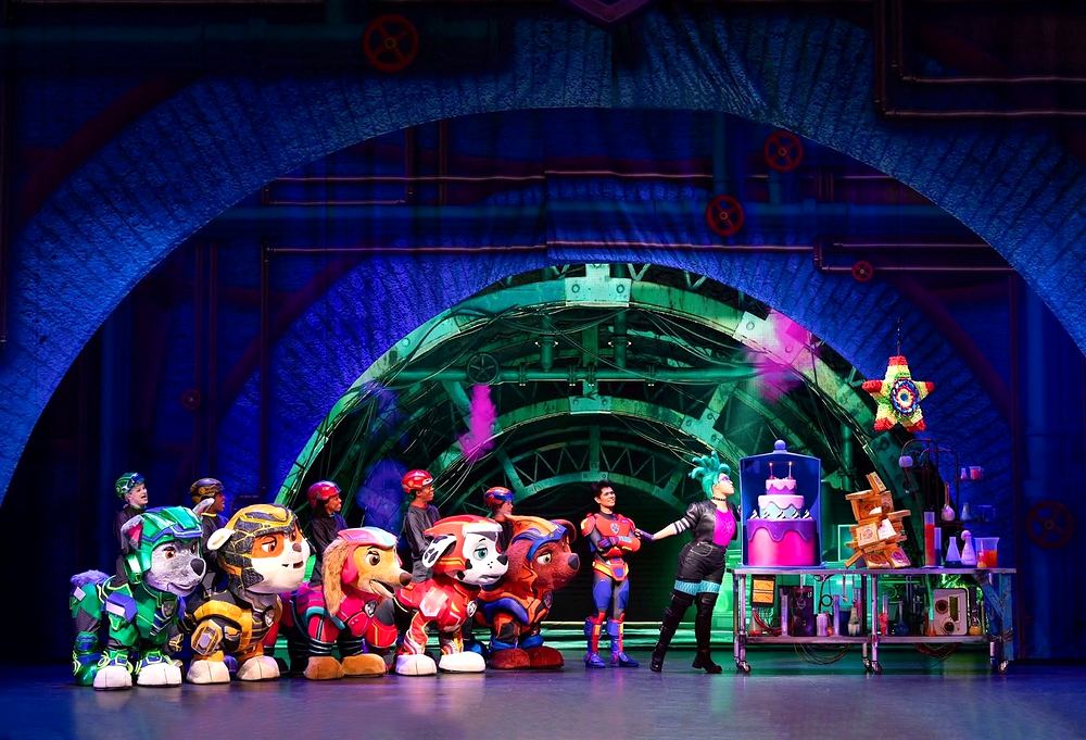 PAW Patrol Live! A Mighty Adventure: Rocky, Rubble, Skye, Marshall and Zuma in Mighty Pups armor face villain Victoria Vance in black with a green mohawk. Costume design by Cynthia Nordstrom