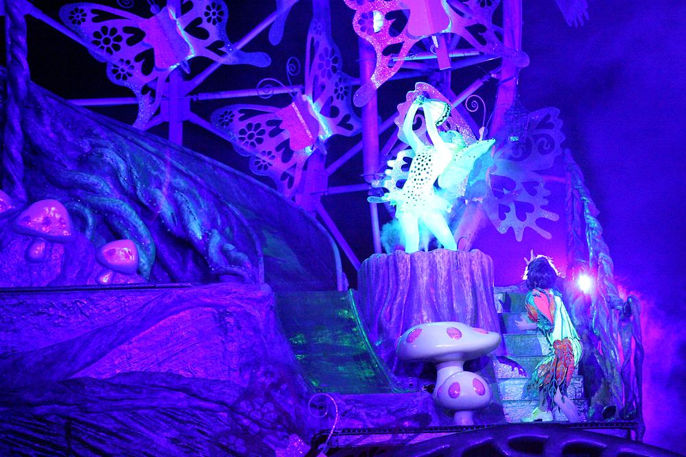 Glowing fairy figure on a stump in a purple-lit forest set, Peter Pan's Neverland, USJ. Costume design by Cynthia Nordstrom