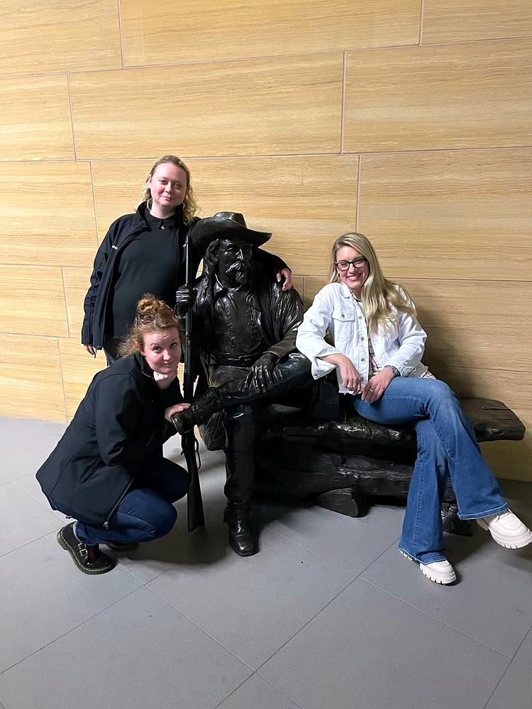 Cynthia Nordstrom and friends posing with a bronze statue on a bench