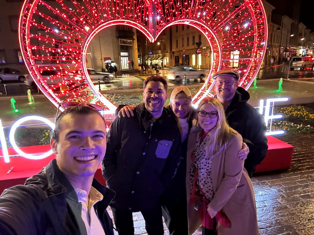 Cynthia Nordstrom with friends in front of a glowing heart light sculpture at night