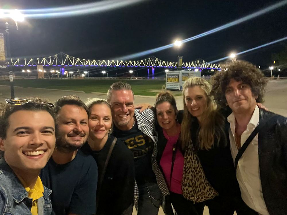 Cynthia Nordstrom with a group of friends at night by a river and a lit-up bridge