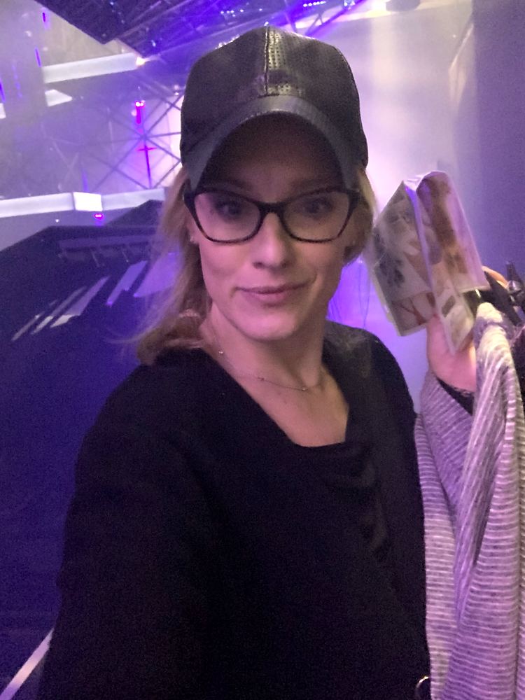 Selfie of Cynthia Nordstrom in a cap and glasses under purple light