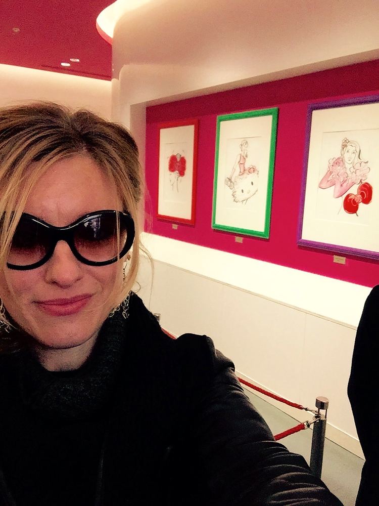 Selfie of Cynthia Nordstrom in sunglasses in front of framed artwork