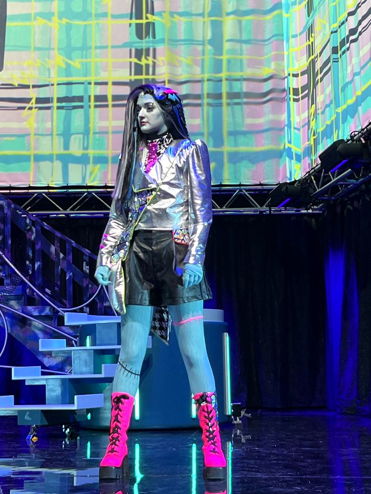 Frankie Stein in a silver jacket, black shorts and pink platform boots, Monster High Live. Costume design by Cynthia Nordstrom