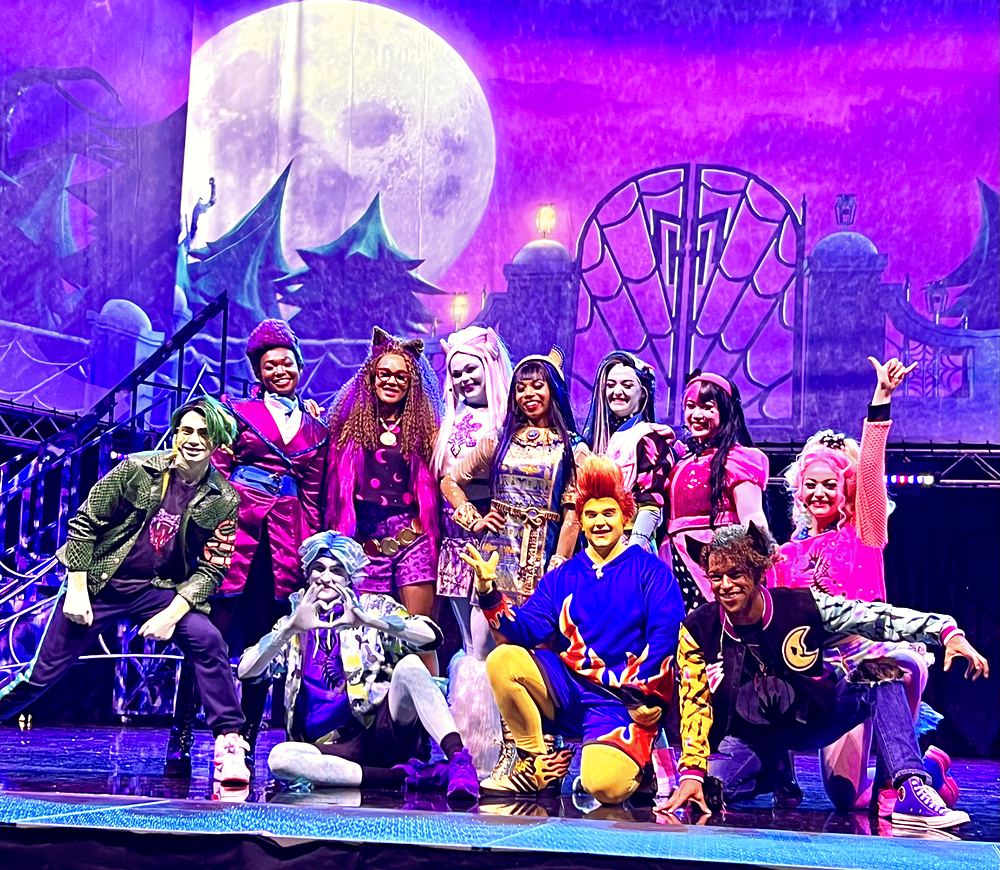 Full cast in colorful monster looks posing under a purple moon, Monster High Live. Costume design by Cynthia Nordstrom