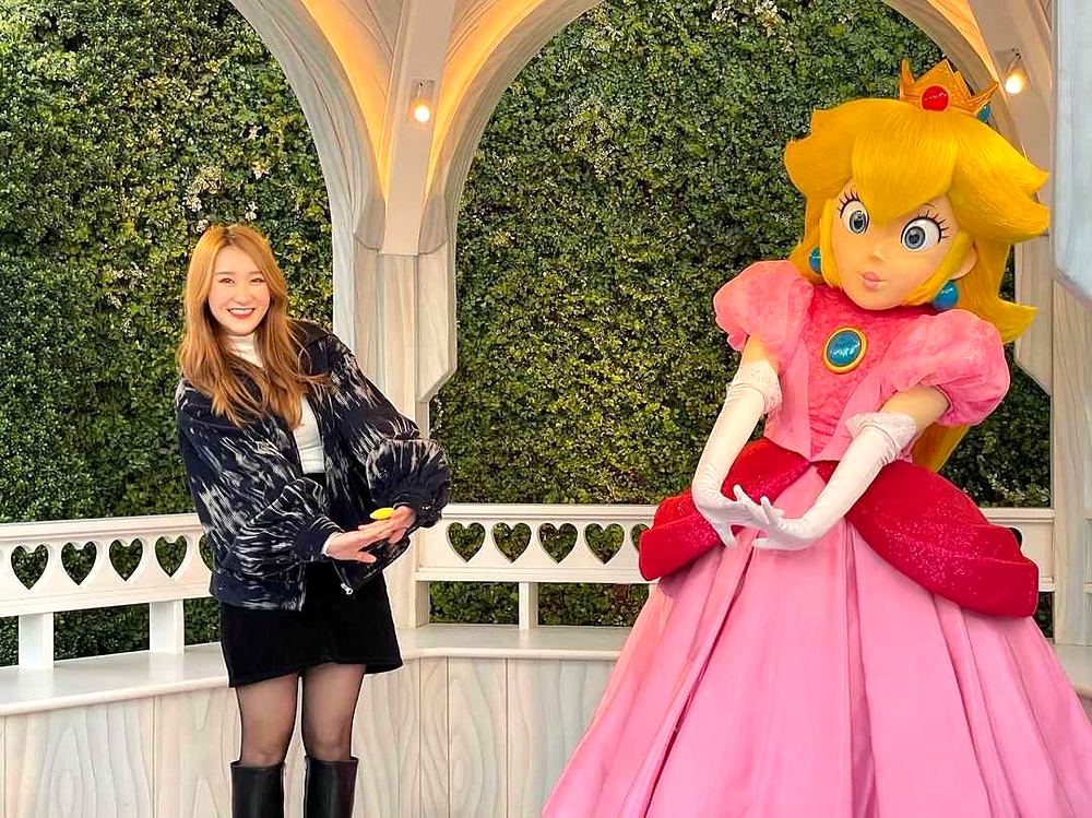 Princess Peach posing for a photo with a guest at Super Nintendo World. Costume design by Cynthia Nordstrom
