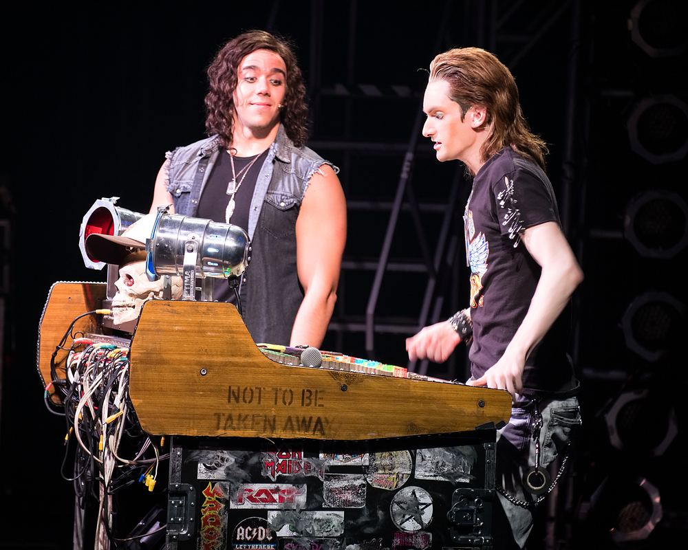 Two rockers in a denim vest and black tee at the bar set, Rock of Ages. Costume design by Cynthia Nordstrom