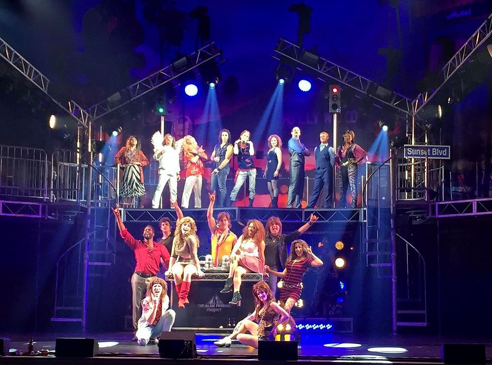 Full company in colorful 1980s costumes across the two-level set, Rock of Ages. Costume design by Cynthia Nordstrom
