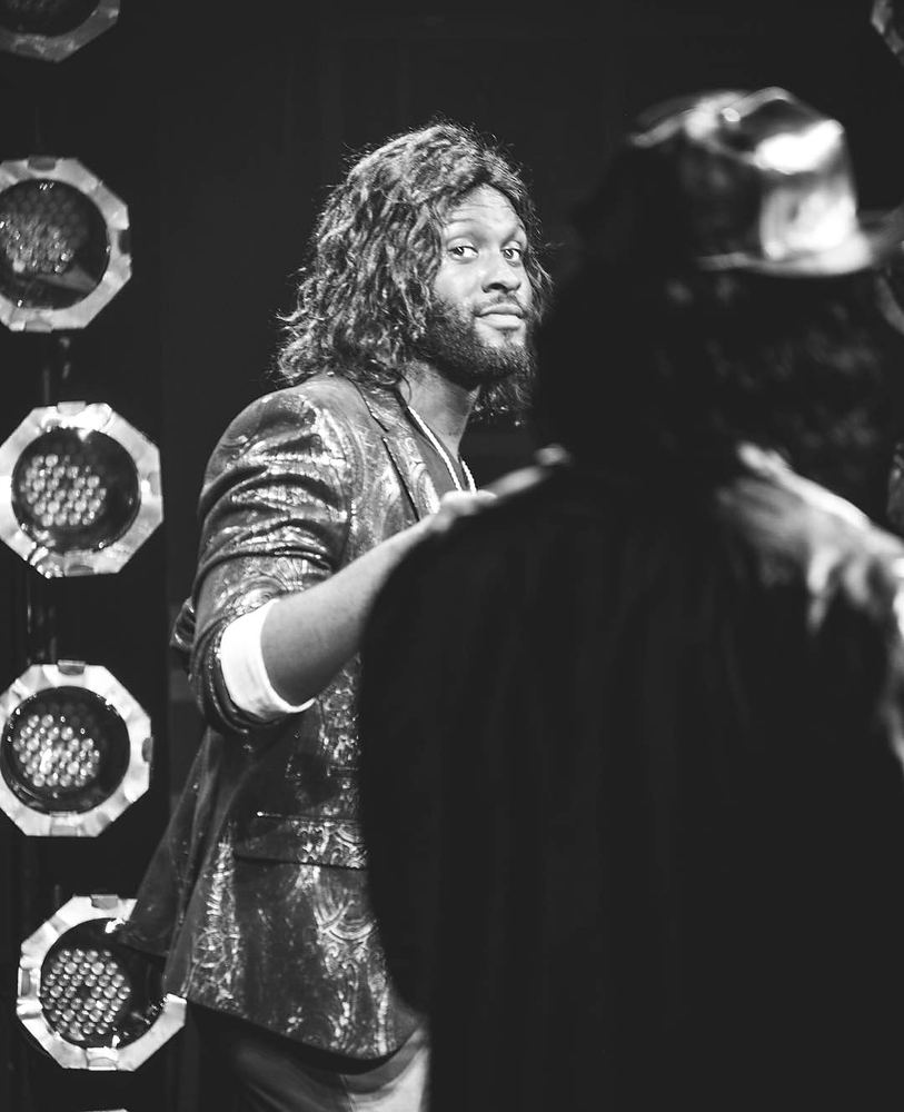 Rocker in a sequined jacket with long curls facing a man in a cowboy hat, Rock of Ages. Costume design by Cynthia Nordstrom