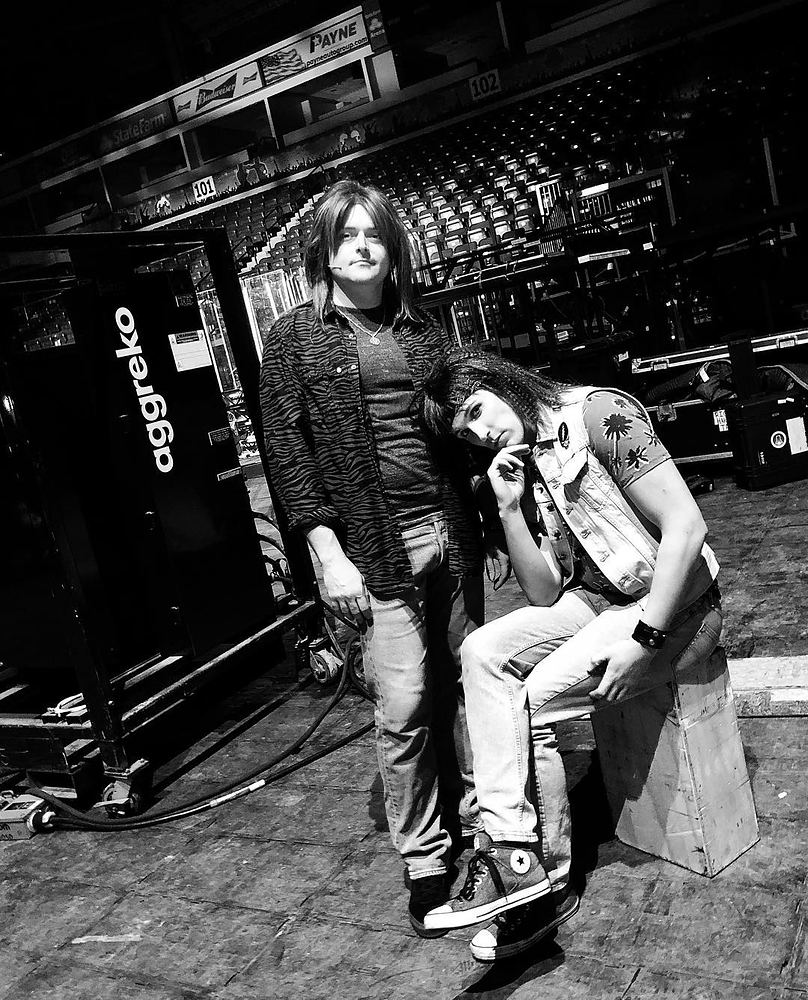 Two rockers in leather jacket, studded vest and jeans by road cases, Rock of Ages. Costume design by Cynthia Nordstrom