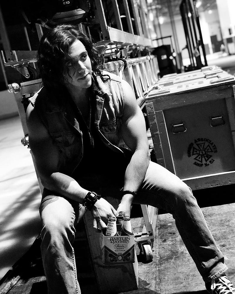 Long-haired rocker in a sleeveless vest and jeans backstage, Rock of Ages. Costume design by Cynthia Nordstrom