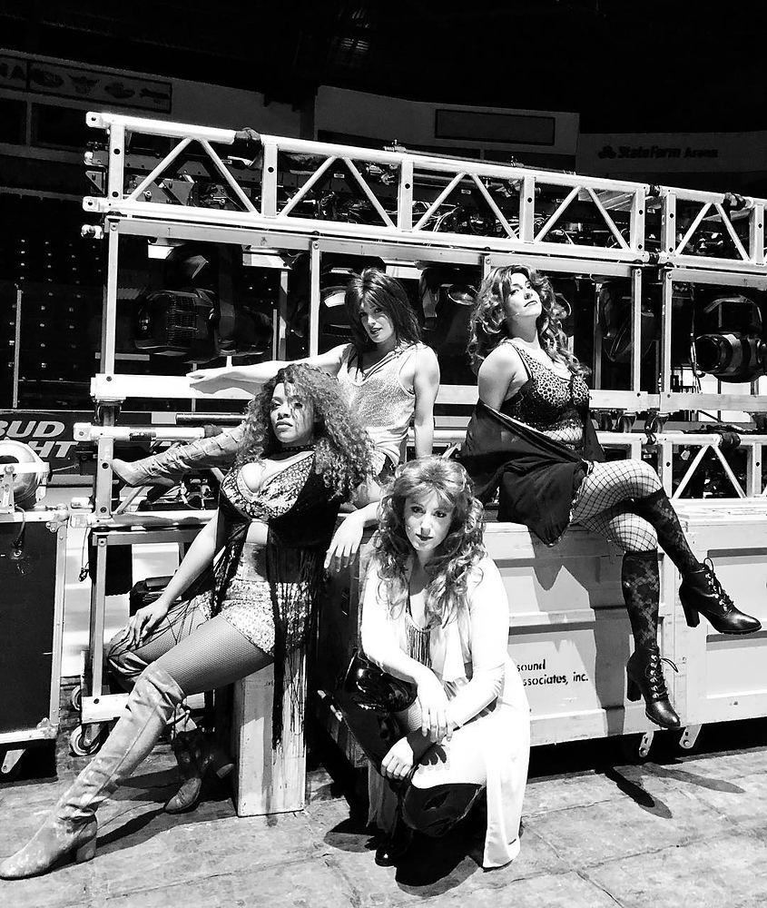 Four women in lace, fishnets and boots posing on road cases, Rock of Ages. Costume design by Cynthia Nordstrom