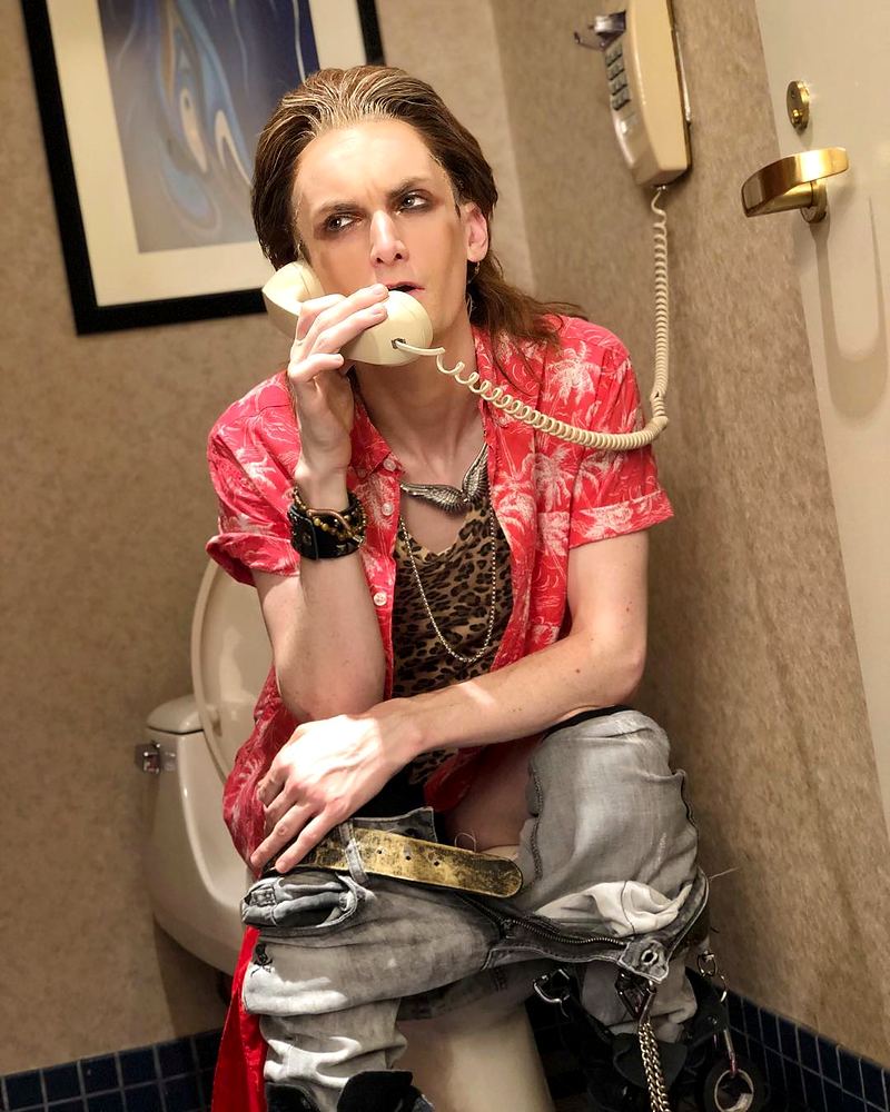 Rocker in a red floral shirt and chains on a hotel phone, a comic backstage shot, Rock of Ages. Costume design by Cynthia Nordstrom
