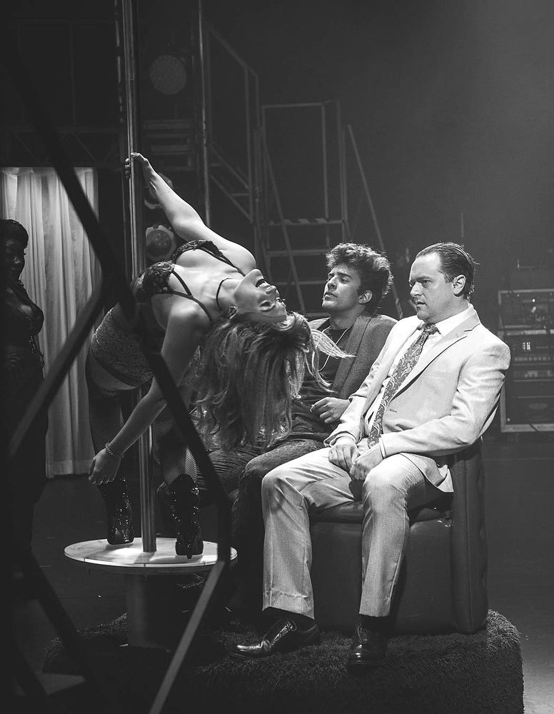 Dancer on a pole beside two men in suits, black and white, Rock of Ages. Costume design by Cynthia Nordstrom
