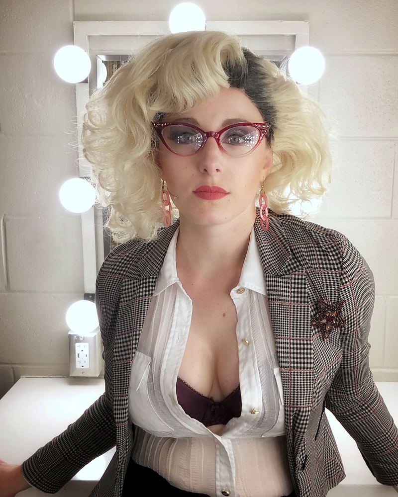 Woman in cat-eye glasses, platinum curls and a plaid blazer in a dressing room, Rock of Ages. Costume design by Cynthia Nordstrom