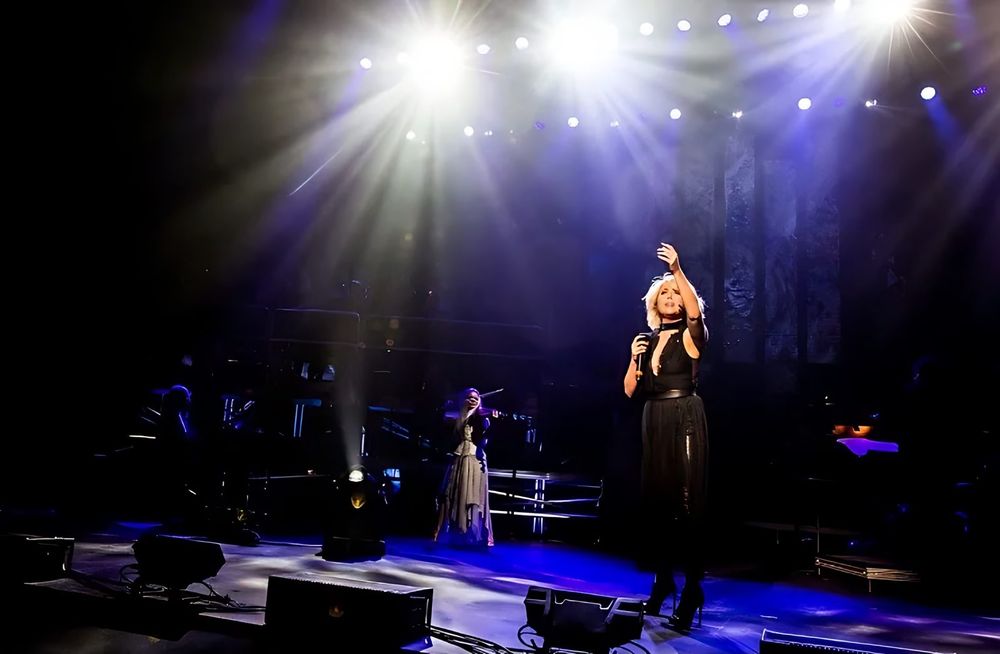 Singer alone on a wide stage under bright spotlights, Rocktopia. Costume design by Cynthia Nordstrom
