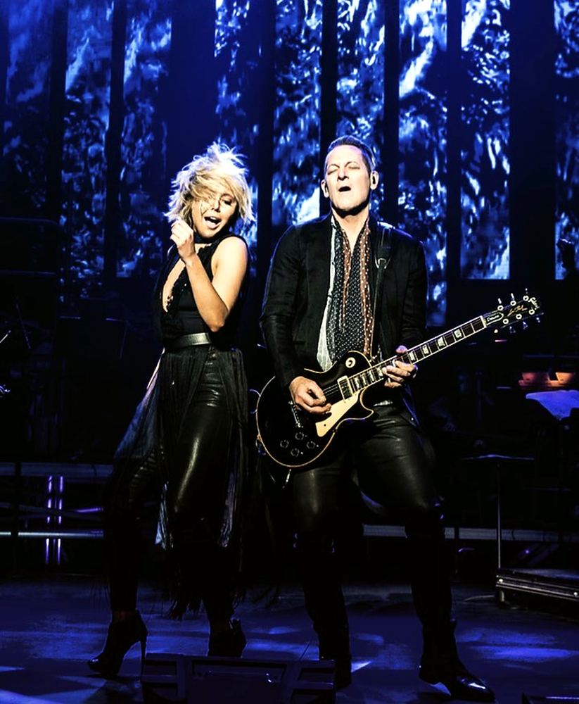 Blonde singer in black and guitarist in a black suit, Rocktopia. Costume design by Cynthia Nordstrom