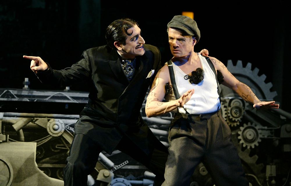 Two comic actors in vintage suspenders and black suit before a gear set, Silent Laughter. Costume design by Cynthia Nordstrom