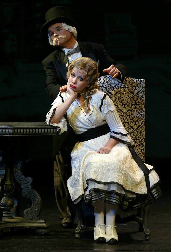 Heroine in a white eyelet dress seated beside a villain in a top hat, Silent Laughter. Costume design by Cynthia Nordstrom