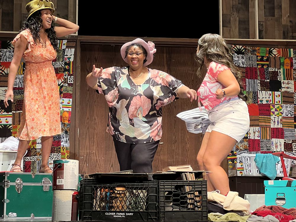 Three women in a peach sundress, floral top and a pink tee on a bedroom set, Sistas. Costume design by Cynthia Nordstrom