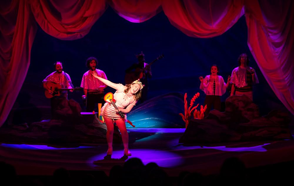 Dancer in pink mid-leap with sailors in red and white, Spells of the Sea. Costume design by Cynthia Nordstrom